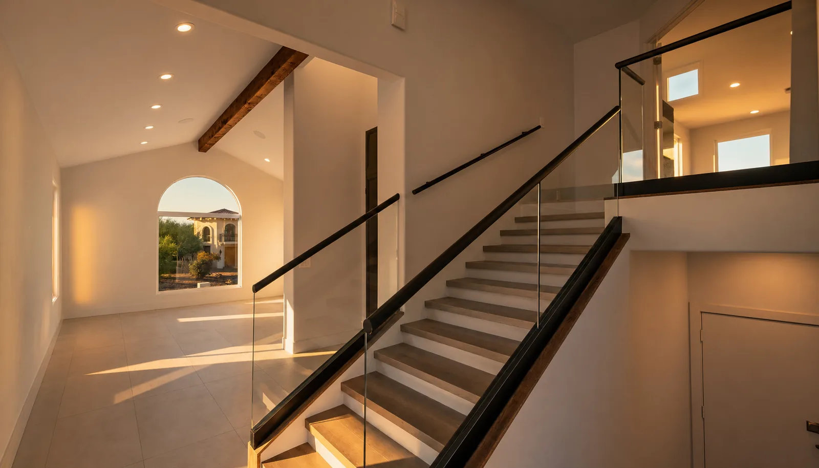 Open stair with a structural glass guardrail and warm oak treads in a completed Scottsdale remodel